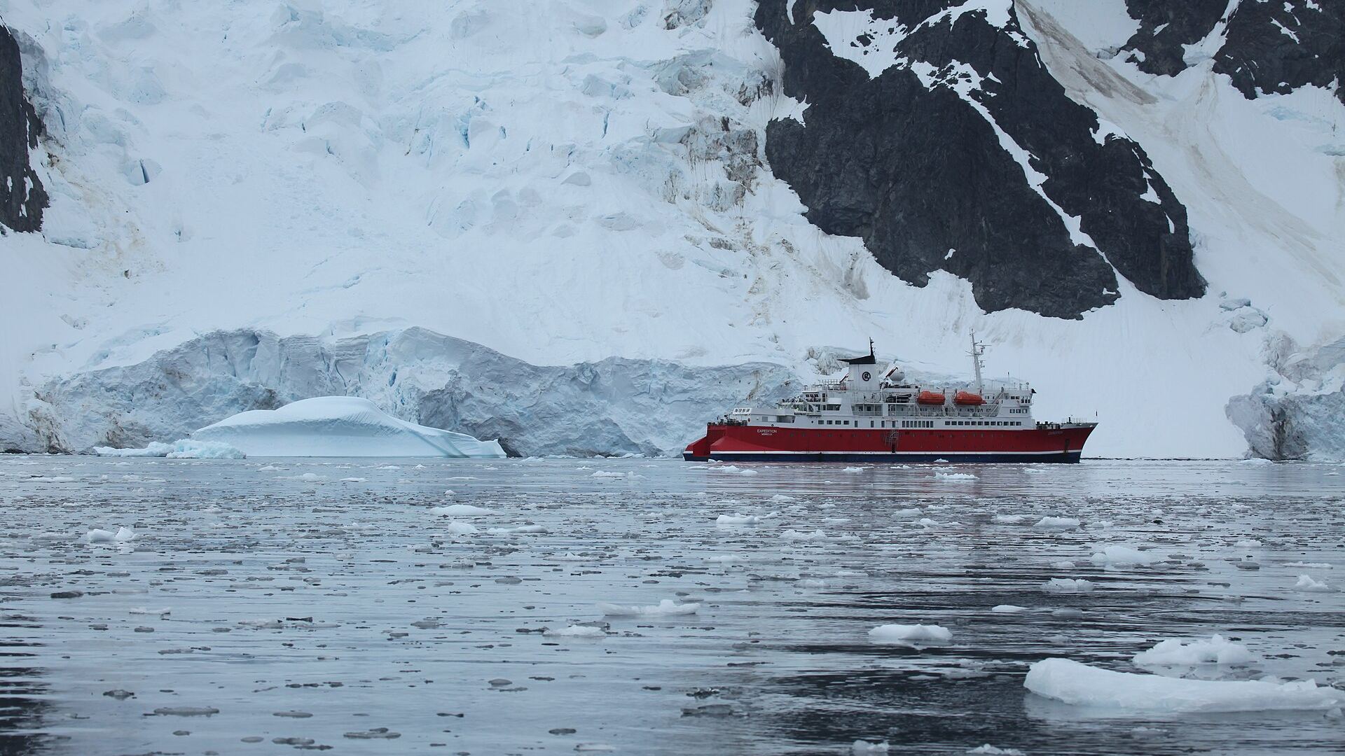 Small expedition ship navigating between icebergs in Antarctica